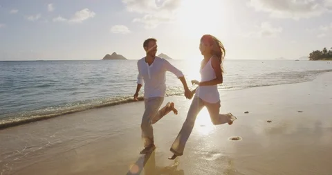 Vacation couple at beach at sunset romantic holding hands running playful Stock Footage