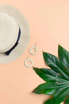 Vacation flat lay composition. Green leaf, straw hat, wicker earrings. Stock Photos