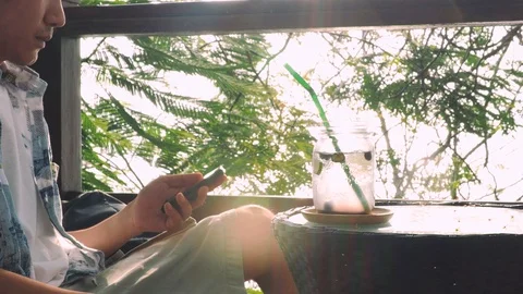 In vacation of a man sit use smartphone and drink fruit beverage under tree. Stock Footage 109588304