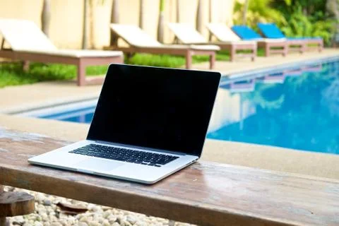 Vacation work with laptop on bench at pool Stock Photos