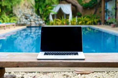 Vacation work with laptop on bench at pool Stock Photos