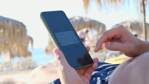 A vacationer using a meal ordering app from his beach location, curating his Stock Footage 318825443