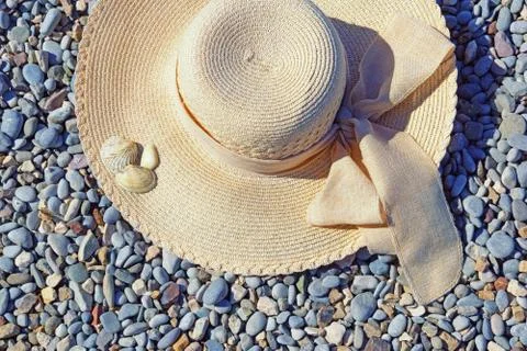 Vacations concept. Sun hat on pebble beach on sunny day Stock Photos