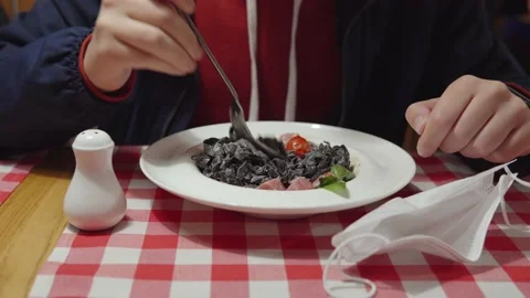 A vaccinated man eats black pasta with cuttlefish ink and fresh tuna. Quarantine Stock Footage 161931059