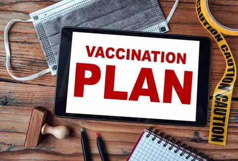 Vaccination plan. Tablet computer, face mask, caution tape and stationery Stock Photos
