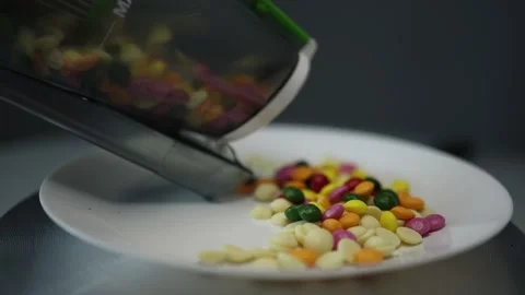 A vacuum cleaner container empties colorful candies onto a white plate. The imag Stock Footage 300021920