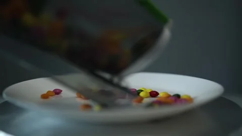 A vacuum cleaner container emptying colorful candies onto a white plate. The ima Stock Footage 300021881