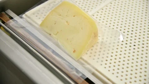 Vacuum packaging cheese slice with hands in black gloves on a perforated tray Stock Footage 336677915