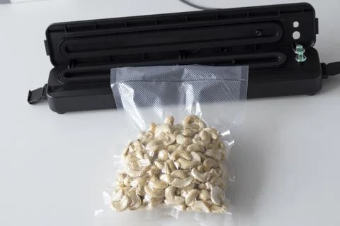Vacuum packaging machine and vacuum bagged nuts. Device for packing food on a Stock Photos