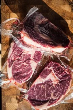 Vacuum packed beef meat steak on wood cutting board Stock Photos