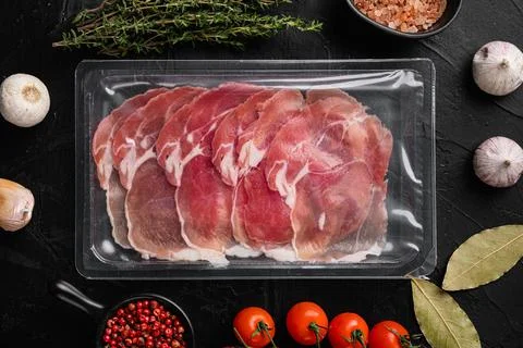 Vacuum packed serrano ham, on black dark stone table background, top view fla Stock Photos