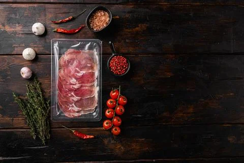 Vacuum packed serrano ham, on old dark wooden table background, top view flat Stock Photos