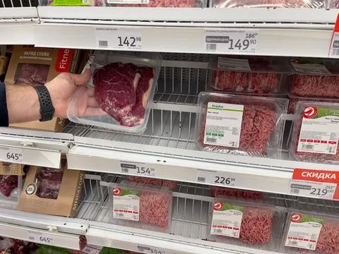 Vacuum packing of beef on display case. A man's hand holds a package of beef. Stockfoto's