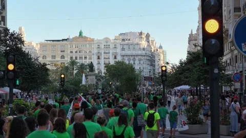VALENCIA, SPAIN - 2026/09/12: Small group crosses plaza near traffic light in. Stock Footage 345450735