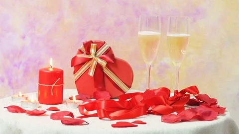 Valentine table with two glasses of champagne , red ribbon  and flamed candles Video stock 71640786