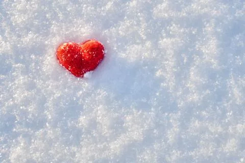 Valentine's day background with a red wool heart lying on the white snow Photos