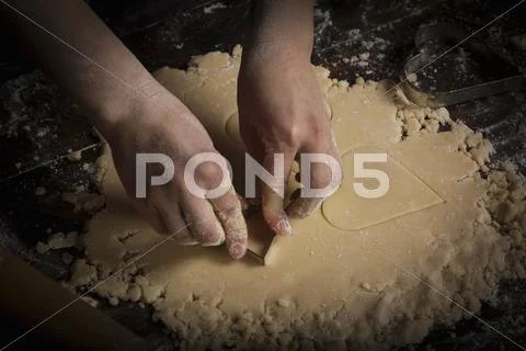 Valentine's Day baking, woman cutting out heart shaped biscuits from dough. Stock Photos