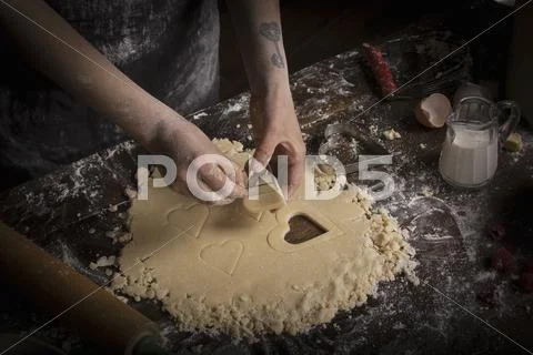 Valentine's Day baking, woman cutting out heart shaped biscuits from dough. Stock Photos