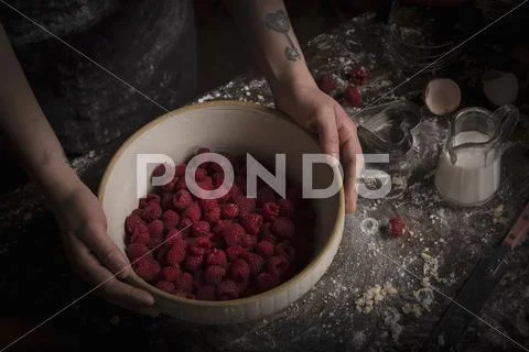 Valentine's Day baking. A woman preparing raspberries in a bowl. Stock Photos