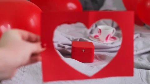 Valentine's Day breakfast with a gift on a bed decorated with heart-shaped ballo Stock Footage 298184594