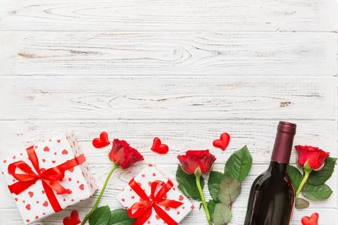 Valentine's day composition with red wine, rose flower and gift box on table. Stock Photos