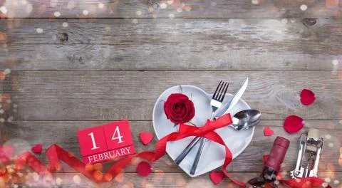 Valentine's Day dinner table layout. Fork, knife, spoon and rose in white pla Stock Photos