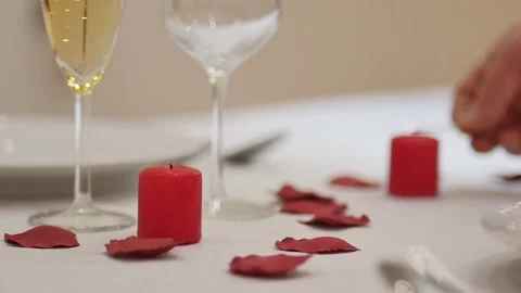 Valentines day dinner table: man waiter or lover lighting up a red love candle Stock Footage 146224954