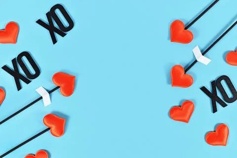 Valentines day flat lay with cupids love arrows and text XOXO on blue Stock Photos
