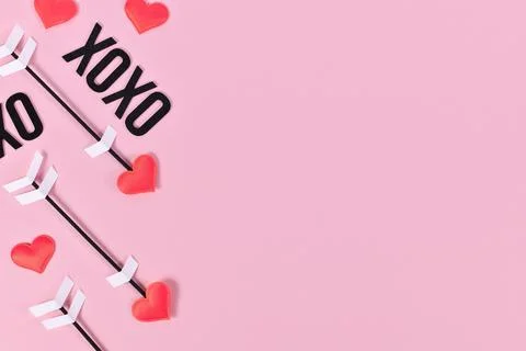 Valentines day flat lay with cupids love arrows and text XOXO on pink Stock Photos