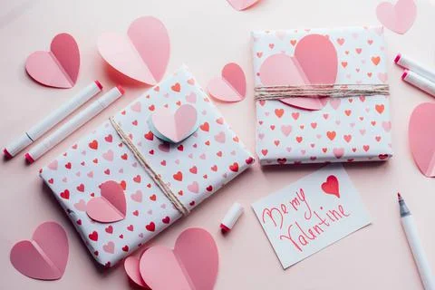 Valentine's day layout with wrapped gifts and big paper hearts on a pink surface Foto stock