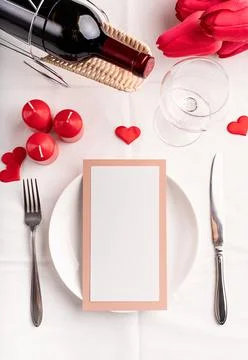 Valentines day table setting with menu, plate, bottle of wine top view, mock  Stock Photos