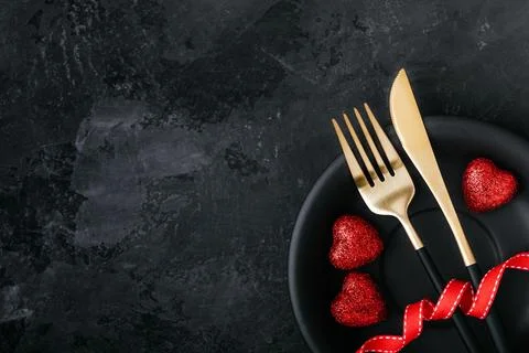Valentine's Day table setting with plate, gold knife, fork, red ribbon and he Stock Photos
