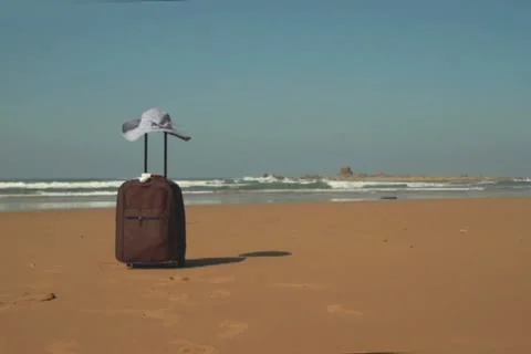 Valise with summer hat on the beach Stockbeeldmateriaal 10892392