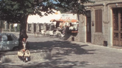 Valldemossa, Mallorca - 1977: Old man rest on stone wall during hot 70s summer Stock Footage 308715101