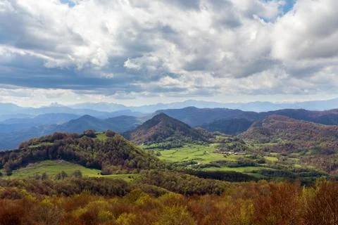 A valley with the green fields on cloudy day. Mountain peaks and heavy clouds Photos
