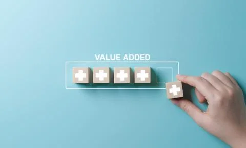 Value add concept. Hand place wooden cube with plus sign on light blue back. Stock Photos