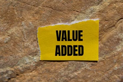 Value added message written on ripped torn yellow paper piece with stone ba.. 스톡 사진