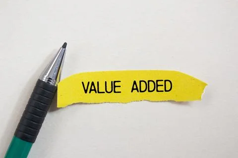 Value added message written on ripped torn yellow paper piece and a pen wit.. Stock Photos