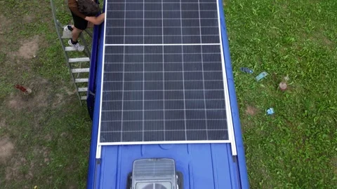 Van build. Young man attaches solar panel on his campervan roof. Solar energy Stock Footage 255799681