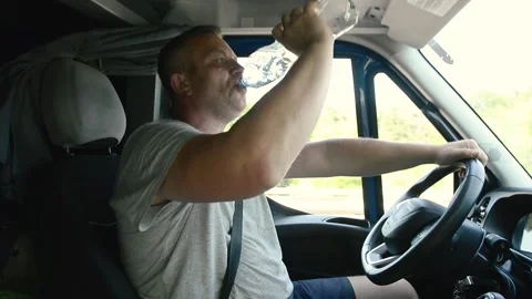 Van driver drinking clean fresh water from a plastic bottle while driving Stock Footage 341825178