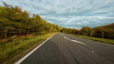 Van driving down countryside highway surrounded by trees and rolling hills under Vídeos de archivo 342501778