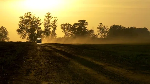 A van driving on a dusty road at sunset Stock Footage 73889577