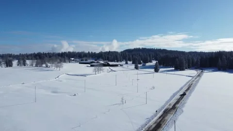 Van driving on road in snowy plain in Jura Switzerland on Holidays drone Stock Footage 168258375