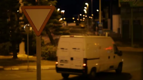 A van at night on a roundabout with a triangular traffic sign. Stock Footage 152792136
