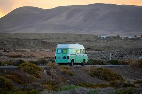 Van parked on a road in a remote area during sunset with mountains and a sm.. Stock Photos