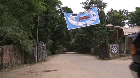 Van passes through open gates of the Sacred Grove. Osun Osogbo festival banner. Stock-Footage 86761046