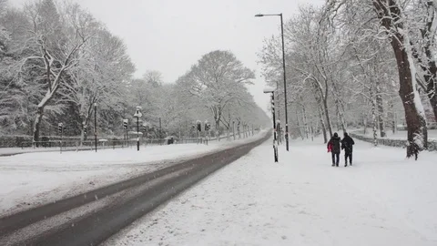 A Van Passes Two People Walking with Sleds in Snowy Conditions 库存影片 83275306