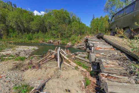 Van SUV with a trailer on a log bridge through the forest river Stock Photos