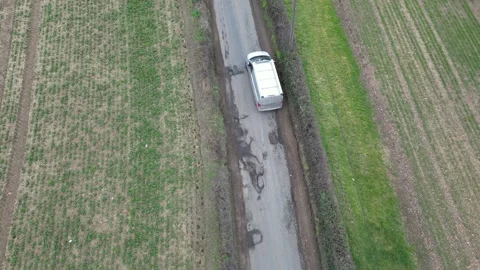 Van swerving around large potholes on UK country road overhead birds eye Stock Footage 234873081