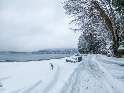 Vancouver's seawall at Third Beach covered in snow, displaying a serene whi.. Stock Photos
